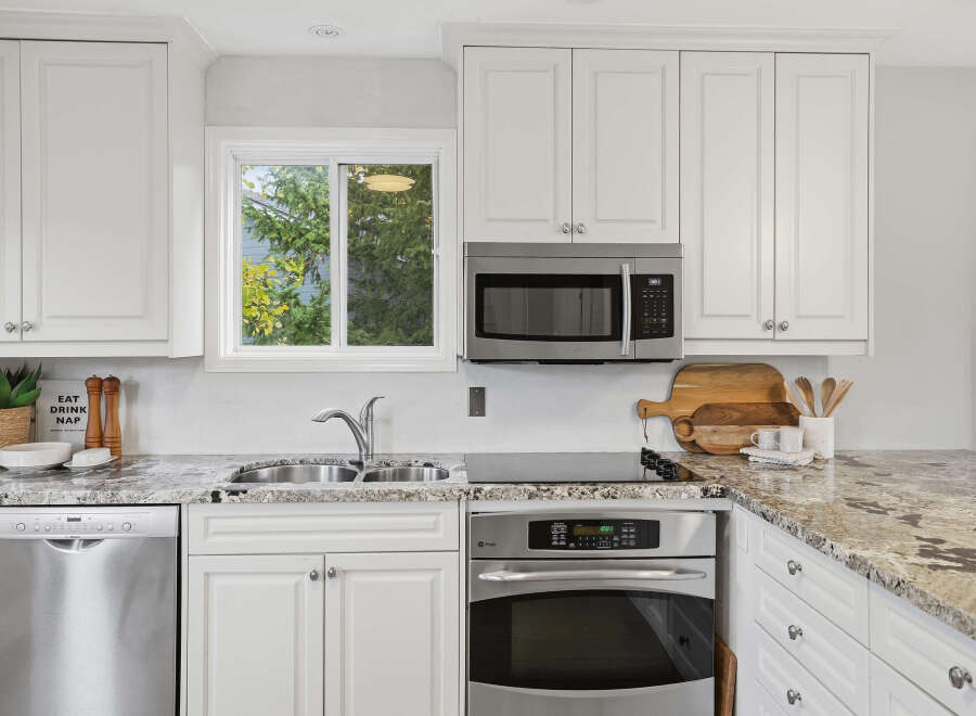 This modern kitchen boasts sleek white cabinetry and granite countertops, offering a bright and airy feel.