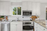 This modern kitchen boasts sleek white cabinetry and granite countertops, offering a bright and airy feel.
