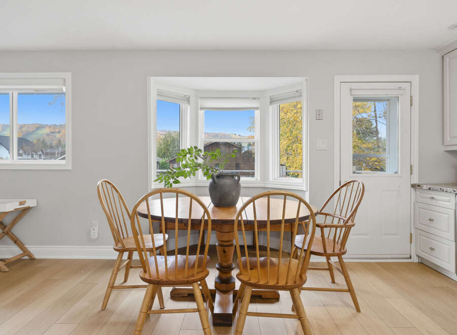 This dining area features a charming wooden pedestal table surrounded by four classic Windsor chairs, creating a cozy and inviting space for meals.