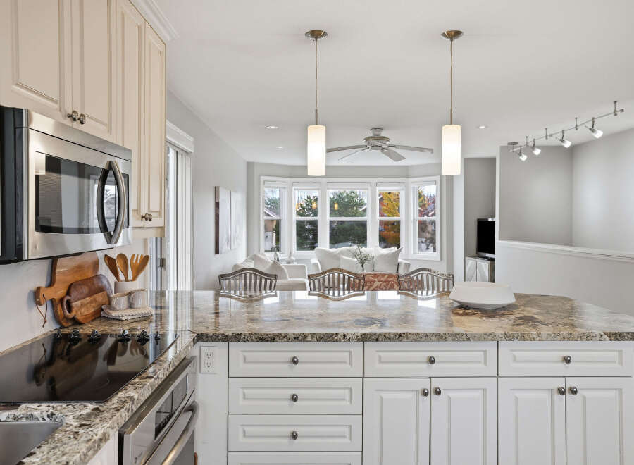 This spacious kitchen boasts elegant cream cabinetry and a stunning granite countertop island, perfect for meal preparation and casual dining.
