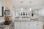 This spacious kitchen boasts elegant cream cabinetry and a stunning granite countertop island, perfect for meal preparation and casual dining.