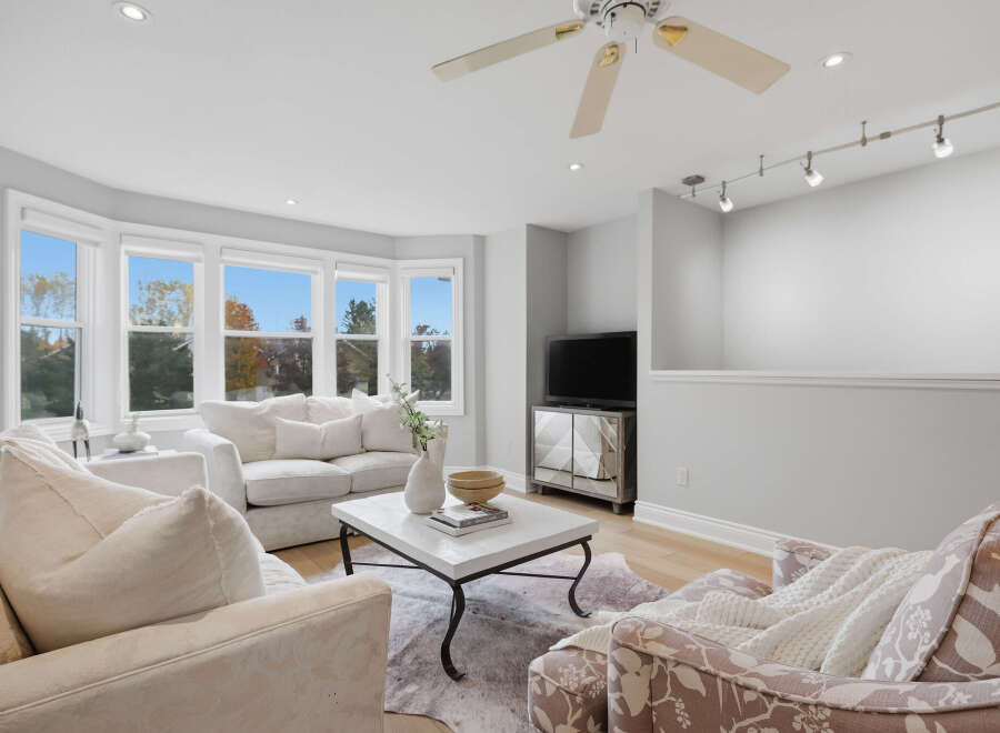 Step into this inviting living room, bathed in natural light from the large bay windows offering scenic views.