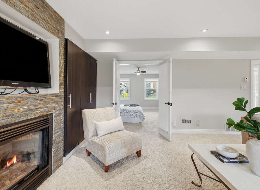 Experience cozy evenings by the fireplace, featuring a stacked stone surround and a mounted television.