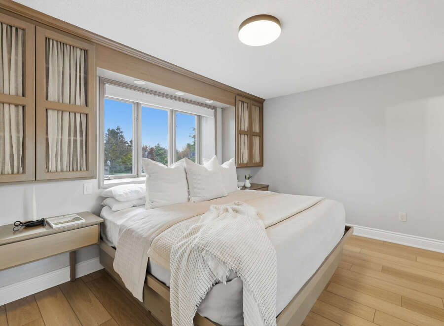 Experience luxurious comfort in this master bedroom, featuring a king-size bed adorned with plush white linens and decorative pillows.