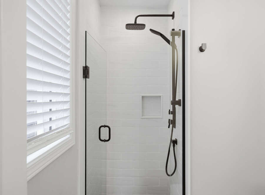 Experience modern luxury in this stunning bathroom featuring a sleek glass-enclosed shower with a rainfall showerhead and handheld wand.