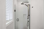 Experience modern luxury in this stunning bathroom featuring a sleek glass-enclosed shower with a rainfall showerhead and handheld wand.