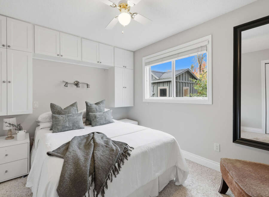 This cozy bedroom features a comfortable queen-size bed adorned with plush decorative pillows and a soft throw blanket.