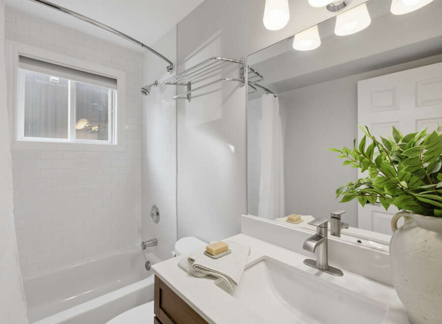 This bright and airy bathroom features a classic white subway tile shower and tub surround, complemented by a sleek chrome showerhead and faucet.