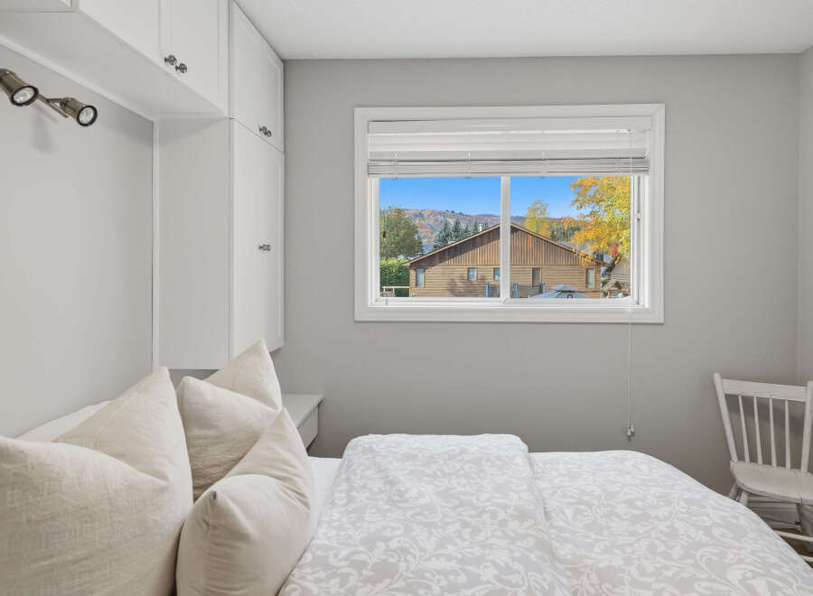 Experience cozy comfort in this inviting bedroom, featuring a plush bed adorned with decorative pillows and a stylish duvet.