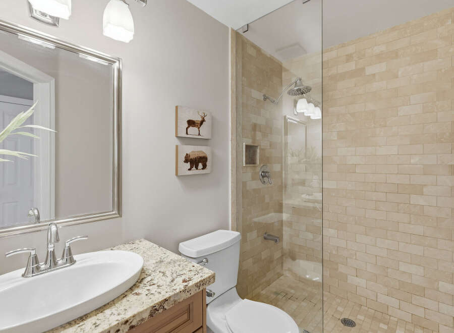 This modern bathroom features a sleek vanity with a granite countertop and a vessel sink, complemented by a large mirror with a silver frame.