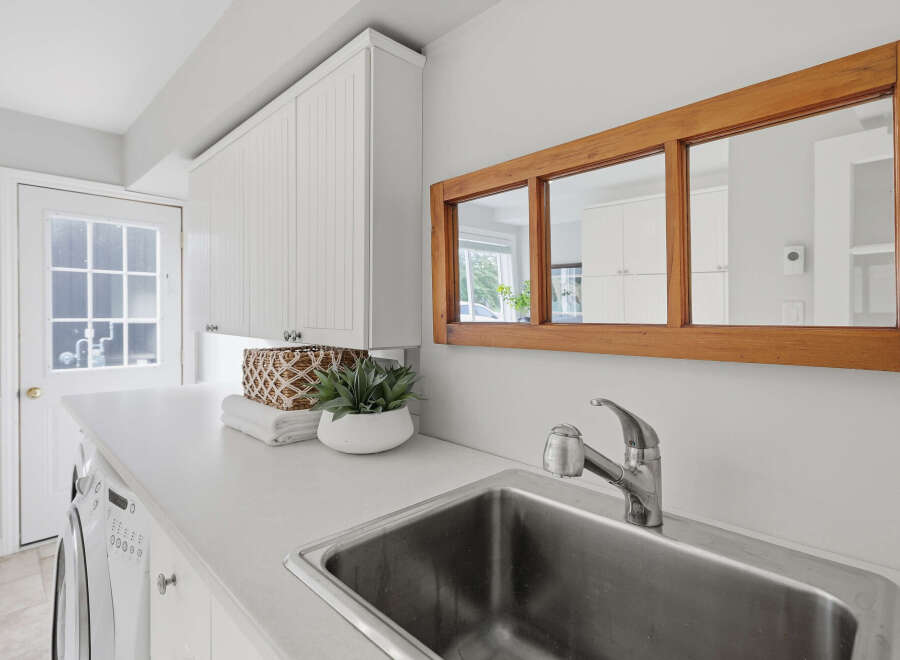 This laundry room features a spacious white countertop with a stainless steel sink and a modern faucet.