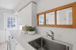 This laundry room features a spacious white countertop with a stainless steel sink and a modern faucet.
