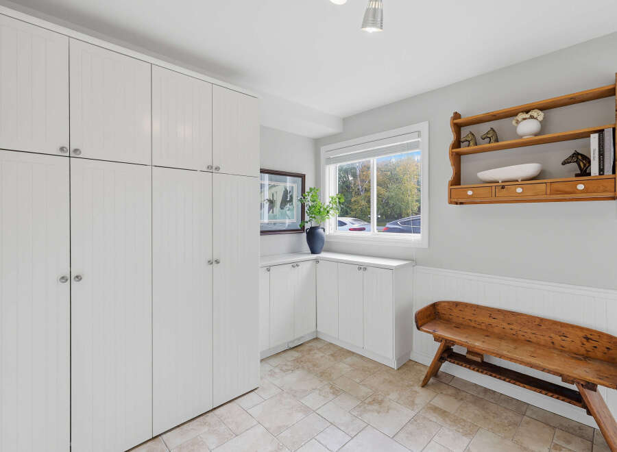 This spacious room features ample storage with floor-to-ceiling white cabinets and additional built-in cabinetry.