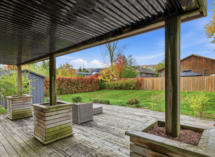 Enjoy outdoor living under this covered patio, complete with a spacious wooden deck perfect for entertaining.
