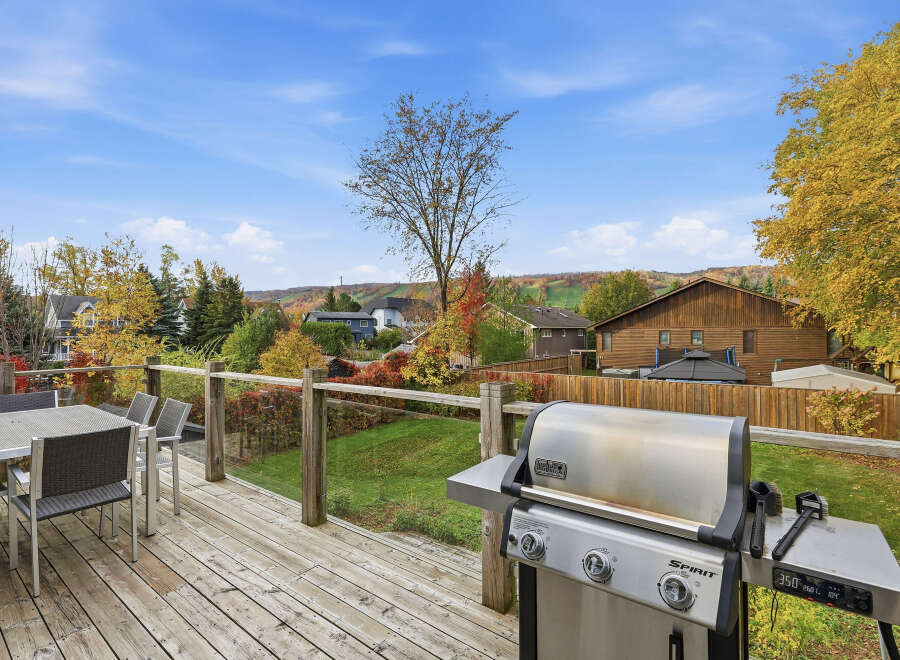 Enjoy outdoor living on this spacious deck, complete with a dining set and a Weber grill, perfect for entertaining.