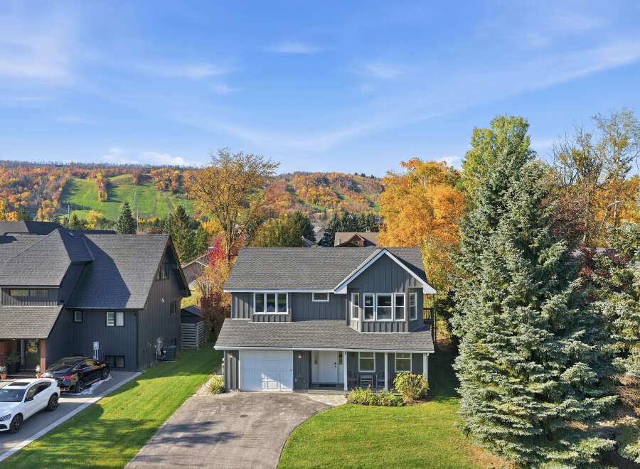 Experience the beauty of autumn from this stunning home, nestled against a backdrop of vibrant fall foliage and a ski hill.