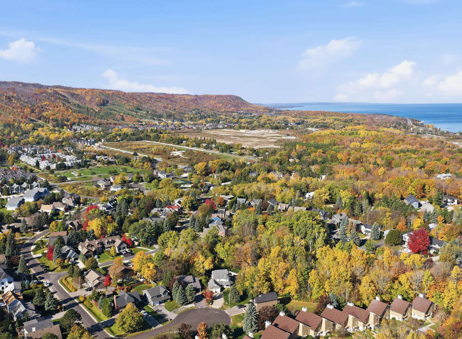 Experience the vibrant beauty of autumn from this stunning aerial view of a residential neighborhood nestled amidst colorful fall foliage.