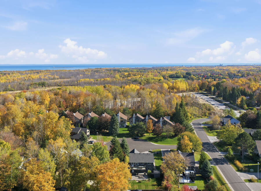 Experience the vibrant beauty of autumn from this stunning aerial view, showcasing a picturesque neighborhood nestled amidst a kaleidoscope of fall foliage.