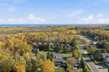 Experience the vibrant beauty of autumn from this stunning aerial view, showcasing a picturesque neighborhood nestled amidst a kaleidoscope of fall foliage.