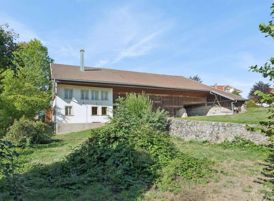 Discover this charming property featuring a traditional white house with multiple windows and a prominent chimney, seamlessly integrated with a rustic wooden barn.