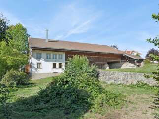 Discover this charming property featuring a traditional white house with multiple windows and a prominent chimney, seamlessly integrated with a rustic wooden barn.