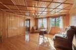 Step into a charming living space bathed in natural light, featuring warm, polished wood paneling on both the walls and the distinctive coffered ceiling.