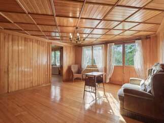 Step into a charming living space bathed in natural light, featuring warm, polished wood paneling on both the walls and the distinctive coffered ceiling.