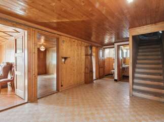 Step into a charming, wood-paneled interior featuring a grand grandfather clock and a cozy seating area.