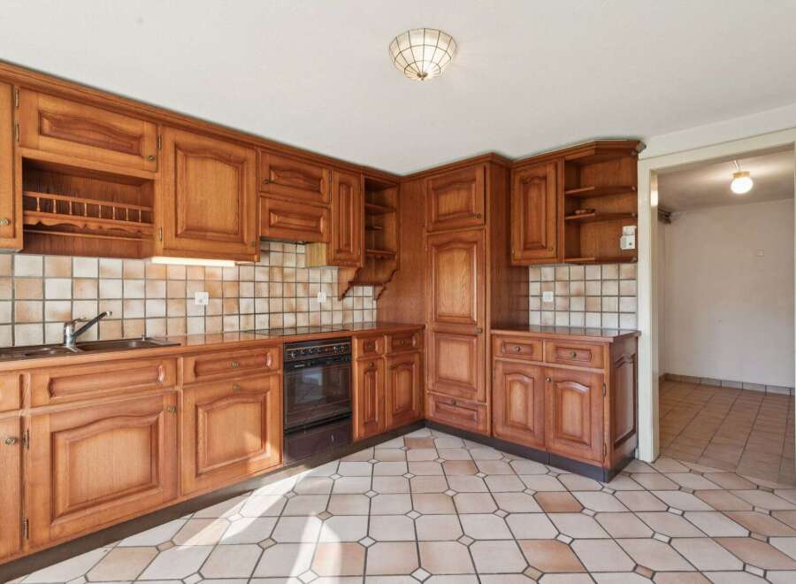 This charming kitchen features warm, honey-toned wooden cabinetry with intricate detailing, offering ample storage and a classic aesthetic.
