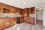This charming kitchen features warm, honey-toned wooden cabinetry with intricate detailing, offering ample storage and a classic aesthetic.