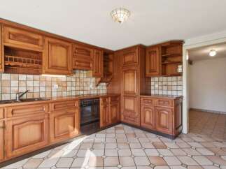 This charming kitchen features warm, honey-toned wooden cabinetry with intricate detailing, offering ample storage and a classic aesthetic.