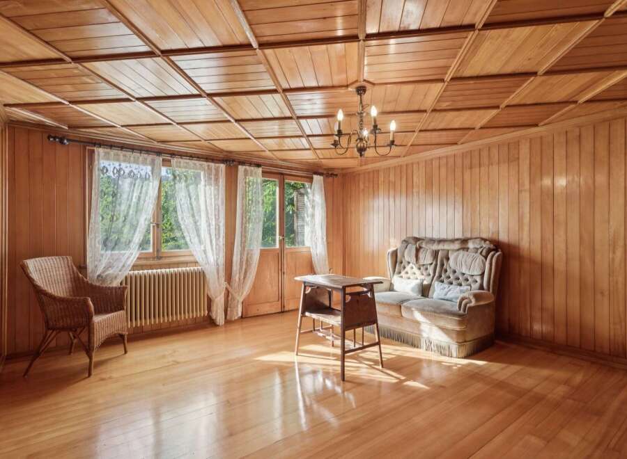 Step into a warm and inviting living space, featuring rich wood paneling and a coffered wood ceiling that exudes rustic charm.