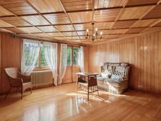 Step into a warm and inviting living space, featuring rich wood paneling and a coffered wood ceiling that exudes rustic charm.
