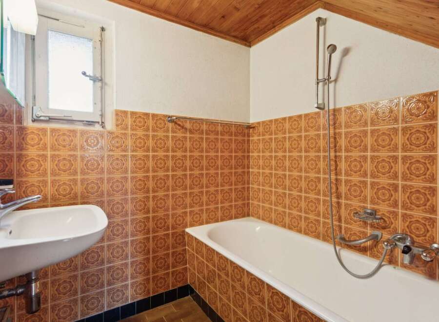 This charming bathroom features a classic design with warm, patterned tiles adorning the walls.