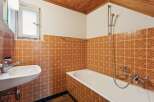 This charming bathroom features a classic design with warm, patterned tiles adorning the walls.