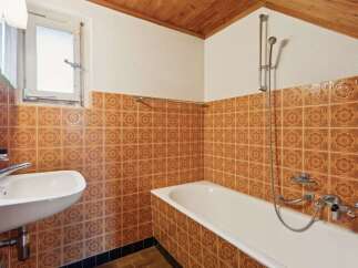 This charming bathroom features a classic design with warm, patterned tiles adorning the walls.