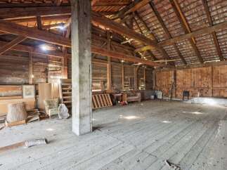 Step into this spacious barn, featuring a robust wooden beam structure and a tiled roof, offering ample room for storage or conversion.