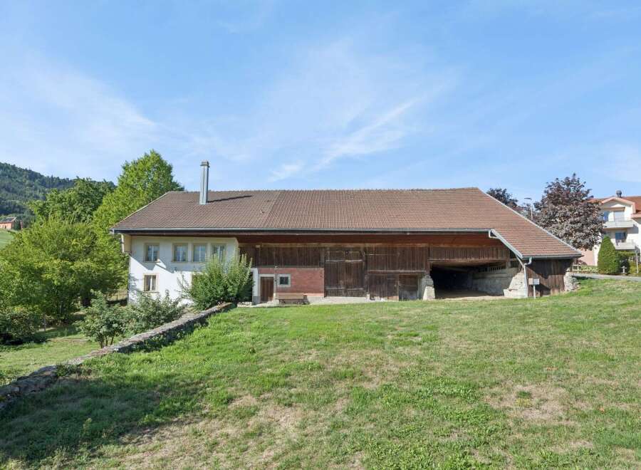 Discover this charming property featuring a spacious barn with traditional wooden doors, perfect for storage or potential conversion.