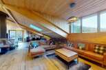 Experience luxurious mountain living in this stunning chalet-style living room, featuring a modern fireplace and a vaulted wooden ceiling with integrated lighting.