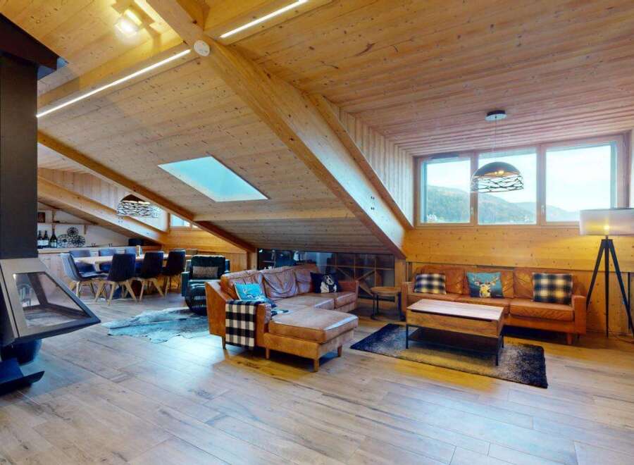 Experience luxury mountain living in this stunning chalet featuring a spacious open-plan living area with a modern fireplace and comfortable leather seating.