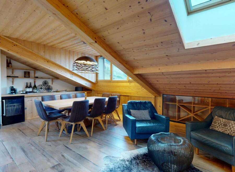 Experience luxurious mountain living in this stunning chalet, featuring a spacious dining area with a large wooden table and comfortable seating, perfect for gathering with loved ones.