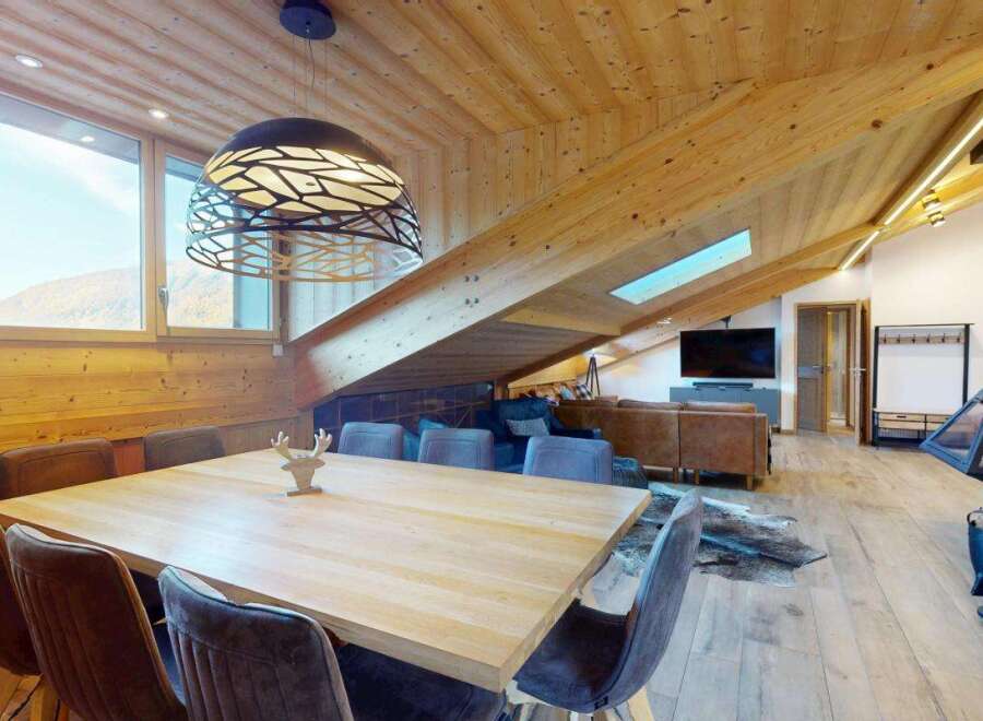 Experience luxurious mountain living in this stunning chalet, featuring a spacious open-plan living area with a modern fireplace and comfortable seating.