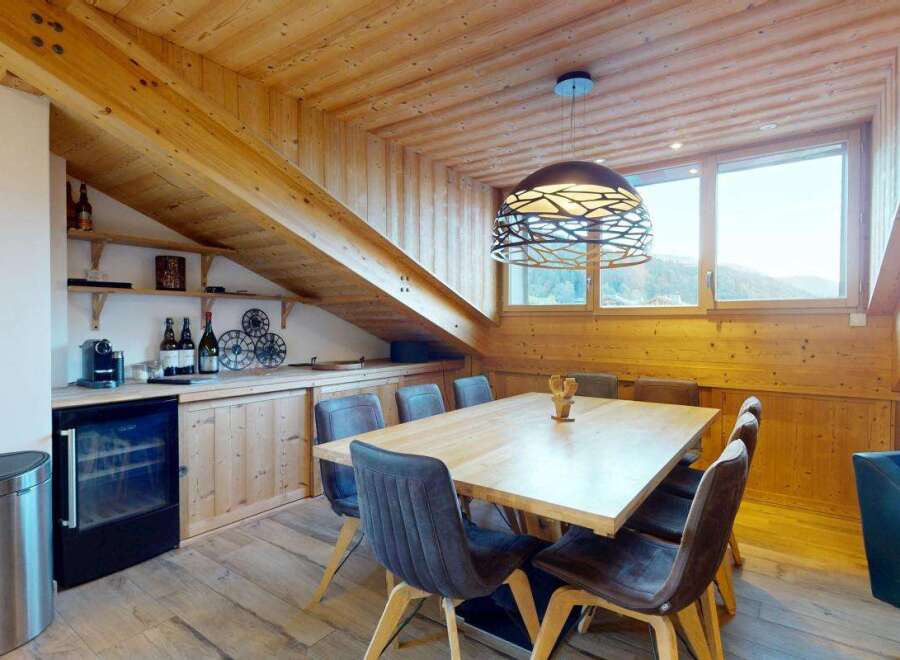 Experience cozy dining in this charming room featuring a rustic wooden ceiling and exposed beams.