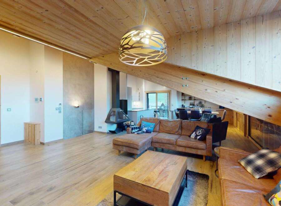 Experience luxury mountain living in this stunning chalet featuring a spacious open-concept living area with a modern fireplace and a large sectional sofa.