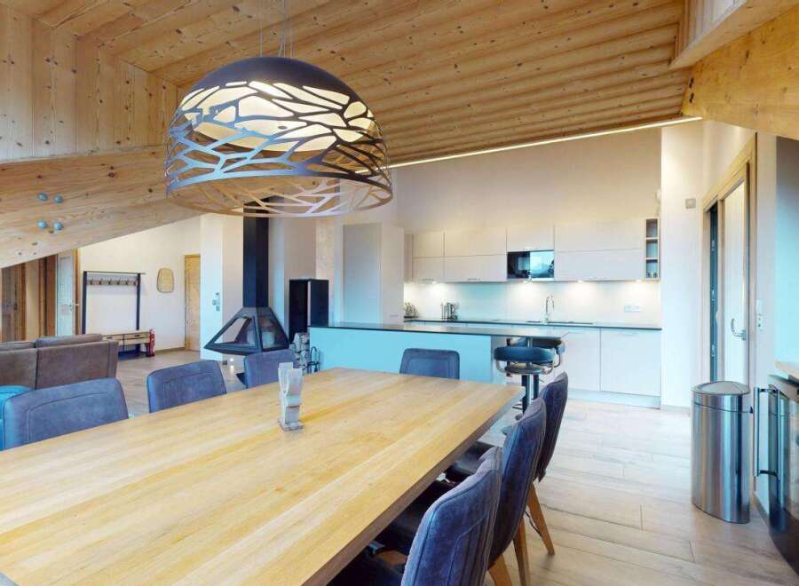 Experience modern alpine living in this stunning open-concept space, featuring a sleek white kitchen with ample counter space and bar seating.