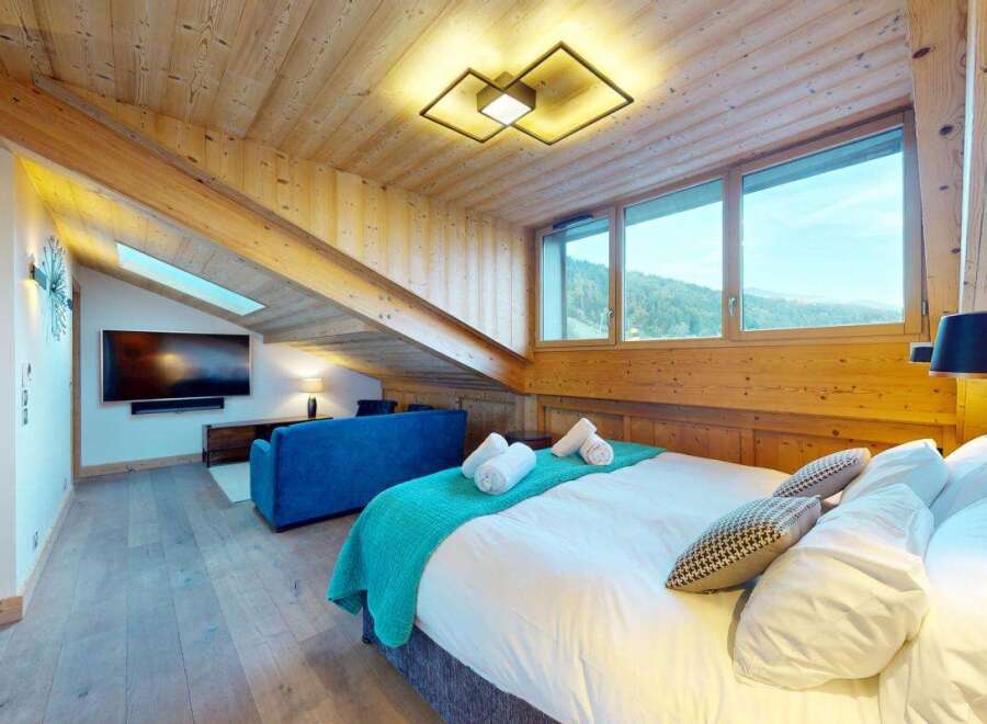 Experience luxury mountain living in this beautifully appointed bedroom featuring a comfortable king-size bed, plush white linens, and a vibrant teal throw blanket.
