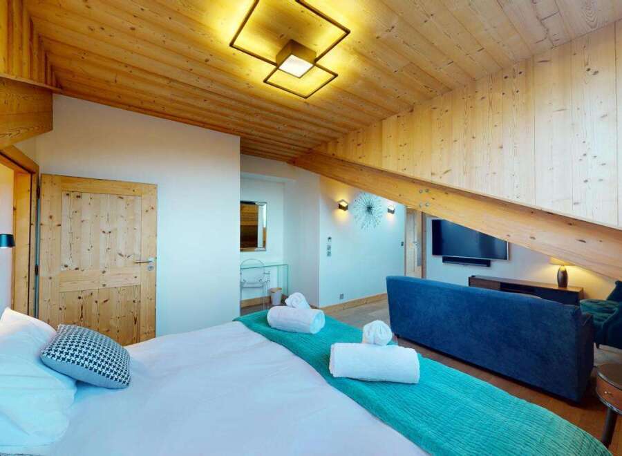 Experience luxurious mountain living in this beautifully appointed bedroom featuring a comfortable bed with crisp white linens and a decorative throw pillow.
