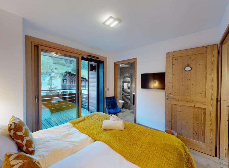 Experience comfort and style in this beautifully appointed bedroom, featuring a plush bed adorned with decorative pillows and a vibrant yellow throw.