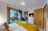 Experience comfort and style in this beautifully appointed bedroom, featuring a plush bed adorned with decorative pillows and a vibrant yellow throw.