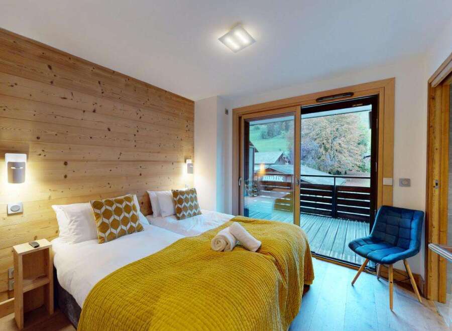 Experience cozy mountain living in this charming bedroom featuring two comfortable beds adorned with warm yellow blankets and decorative pillows.